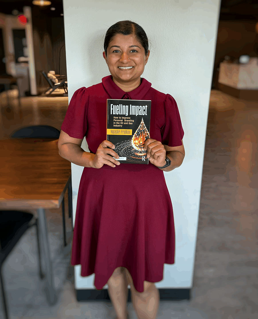 Yogashri "Yoshi" Pradhan holding a copy of Fueling Impact